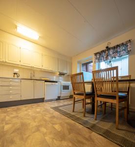 阿比斯库Abisko Hostel的厨房配有白色橱柜和桌椅
