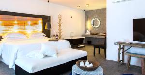 埃利亚海滩Myconian Avaton, a Member of Design Hotels的一间卧室配有一张床、一张书桌和一台电视