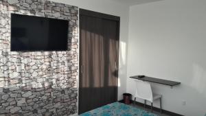 马尼萨莱斯Hotel Rosales Plaza的一间石墙上配有电视的房间