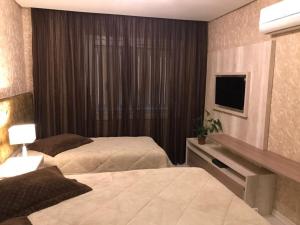 格拉玛多Altos da Bela Vista Gramado centro locação de temporada的酒店客房设有两张床和电视。