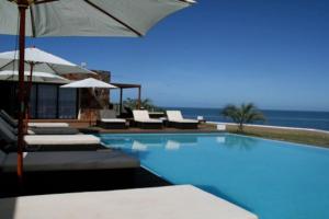 埃斯特角城Quartier Punta Ballena 2 dorm en suite的一个带椅子和遮阳伞的游泳池以及大海