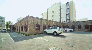 马斯喀特穆特拉酒店的停在砖砌建筑旁边的停车场的白色货车