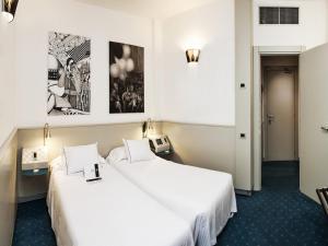 帕多瓦米兰酒店的配有白色床单的酒店客房内的两张床