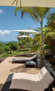 马埃岛Bois Joli的庭院设有两张床和一把遮阳伞。
