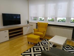萨格勒布ZagrebFun的一间带电视和黄椅的客厅