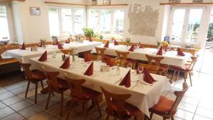 MühlenHotel Restaurant Edelweiss的一间设有桌椅的房间,上面摆放着红色的餐巾