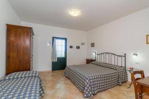 萨杜勒尼亚Agriturismo Valle Martina的一间卧室配有两张床、一张桌子和一把椅子