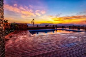 基加利Peponi Living Spaces的甲板上的游泳池,背景是日落