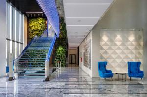 华沙Apartamenty Vola Residence的大楼内带蓝色椅子和楼梯的走廊