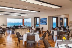 罗萨里奥港Hotel El Mirador de Fuerteventura的餐厅设有桌椅,背景为大海