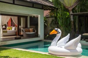 塞米亚克巴厘岛水别墅精品度假Spa酒店的度假村旁边的游泳池里浮着天鹅