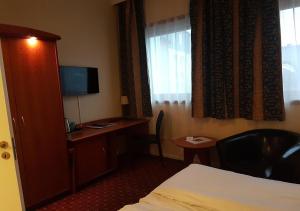特隆赫姆Chesterfield Hotel的酒店客房配有一张床和一张书桌及一台电视