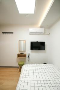 首尔Heima Guesthouse Hongdae的一间卧室配有一张床和一台平面电视