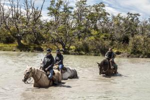 百内三塔日光与马潘帕山林小屋的一群骑马穿越河流的人