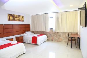瓜亚基尔Hotel Apart Guayaquil Aeropuerto的一间卧室配有两张床、一张桌子和一张书桌