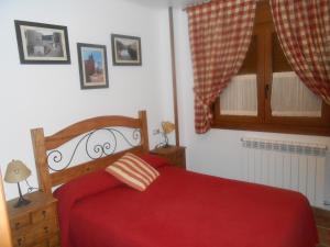 La Virgen de la Vega玛丽亚别墅的一间卧室设有红色的床和窗户。