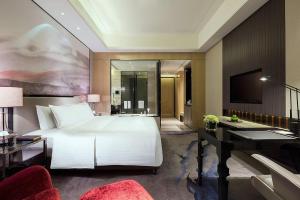武汉武汉富力万达嘉华酒店的卧室配有一张白色大床和一张书桌