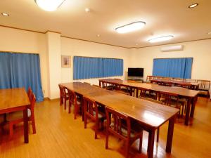 KaminatoKokumin Shukusha Sun Marina的一间设有木桌和椅子的教室,以及蓝色窗帘