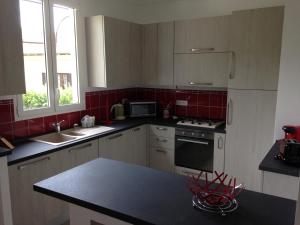 拉特里尼泰Le 43的厨房配有白色橱柜和红色瓷砖