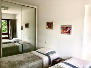 普拉亚多Residencial Enseada Praia do Forte Apto 130的一间卧室配有两张床和镜子