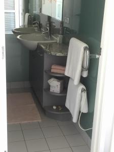 欧尼罗亚Oneroa Bay Villas的浴室配有盥洗盆、镜子和毛巾