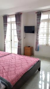 邦美蜀Nhà Nghỉ Hoàng Hoa的卧室配有粉红色的床和平面电视。