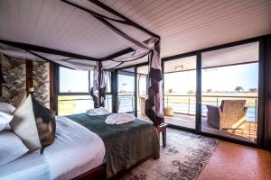 KongolaThe Namushasha River Villa的一间卧室设有一张天蓬床和一个阳台