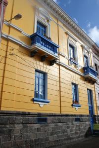 拉塔昆加Hostal Café Tiana的黄色的建筑,设有蓝色的窗户和阳台