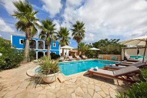 圣米克尔德巴兰Villa Can Coves的一个带躺椅的游泳池以及一间蓝色的房子