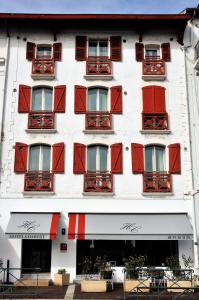 圣让-德吕兹科尔伯特酒店的一座高大的白色建筑,设有红色百叶窗