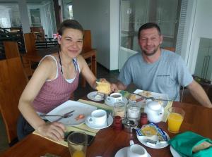 乌斯维塔克伊亚瓦Saprin Beach By Travel Corners的坐在餐桌旁吃食物的男人和女人