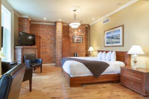 魁北克市格林奥乐酒店的一间卧室设有床铺、电视和砖墙