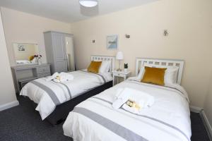 巴利卡斯尔Causeway Coast Apartments Kyla Marine的配有2张床铺的酒店客房,提供白色和橙色枕头