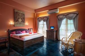 素可泰班乔治酒店的一间卧室拥有橙色的墙壁,配有一张带粉红色枕头的床