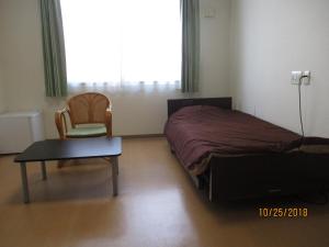 指宿市山彦御宿日式旅馆的一间卧室配有一张床、一把椅子和一张桌子
