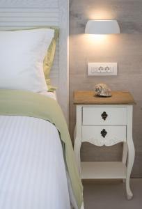 科斯镇White Pearls-Adults Only Luxury Suites的一间卧室配有一张床和一个带灯的床头柜