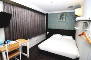新加坡HOTEL JJH Aliwal的一间小卧室,配有一张床和一张书桌