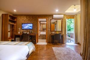 乌库拉斯西沙滩旅馆的一间卧室配有一张床和一张书桌及电视