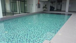 哥打巴鲁Prestige Sky Riverfront的大型游泳池设有蓝色瓷砖地板和窗户
