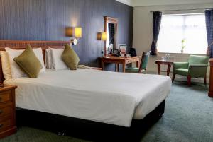 格雷斯瑟罗克Best Western Thurrock Hotel的酒店客房设有一张大床和一张书桌。