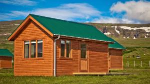 华姆斯唐吉华姆斯唐吉小屋酒店的田野上带绿色屋顶的小木屋