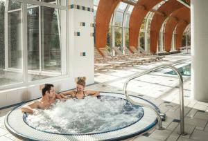 卡罗维发利无忧宫温泉度假酒店的两个男人在一座大楼的热水浴缸里