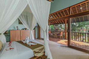 登巴萨Villa D'Carik Bali的一间卧室配有带白色窗帘的床和阳台