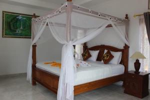 新加拉惹相聚旅馆的卧室配有带白色窗帘的天蓬床
