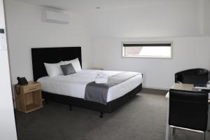 基督城基督城MCM汽车旅馆的一间卧室配有一张床、一张书桌和一个窗户。