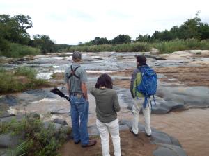 侯斯普瑞特Blyde River Cabins的站在岩石上,看着一条河流的三人
