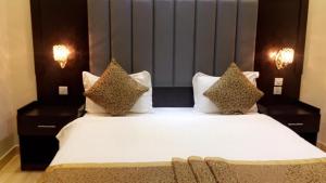 利雅德Al Rafahya Crown的一间卧室配有带白色床单和枕头的床。
