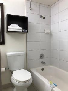 长滩长滩酒店的浴室配有白色卫生间、浴缸和水槽。