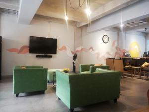 雅加达PINX'S HOSTEL的一间设有绿色椅子和平面电视的等候室
