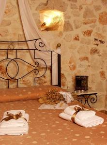 凯里翁雷沃拉传统石头别墅和公寓酒店的一间卧室,在一张石墙床上配有毛巾